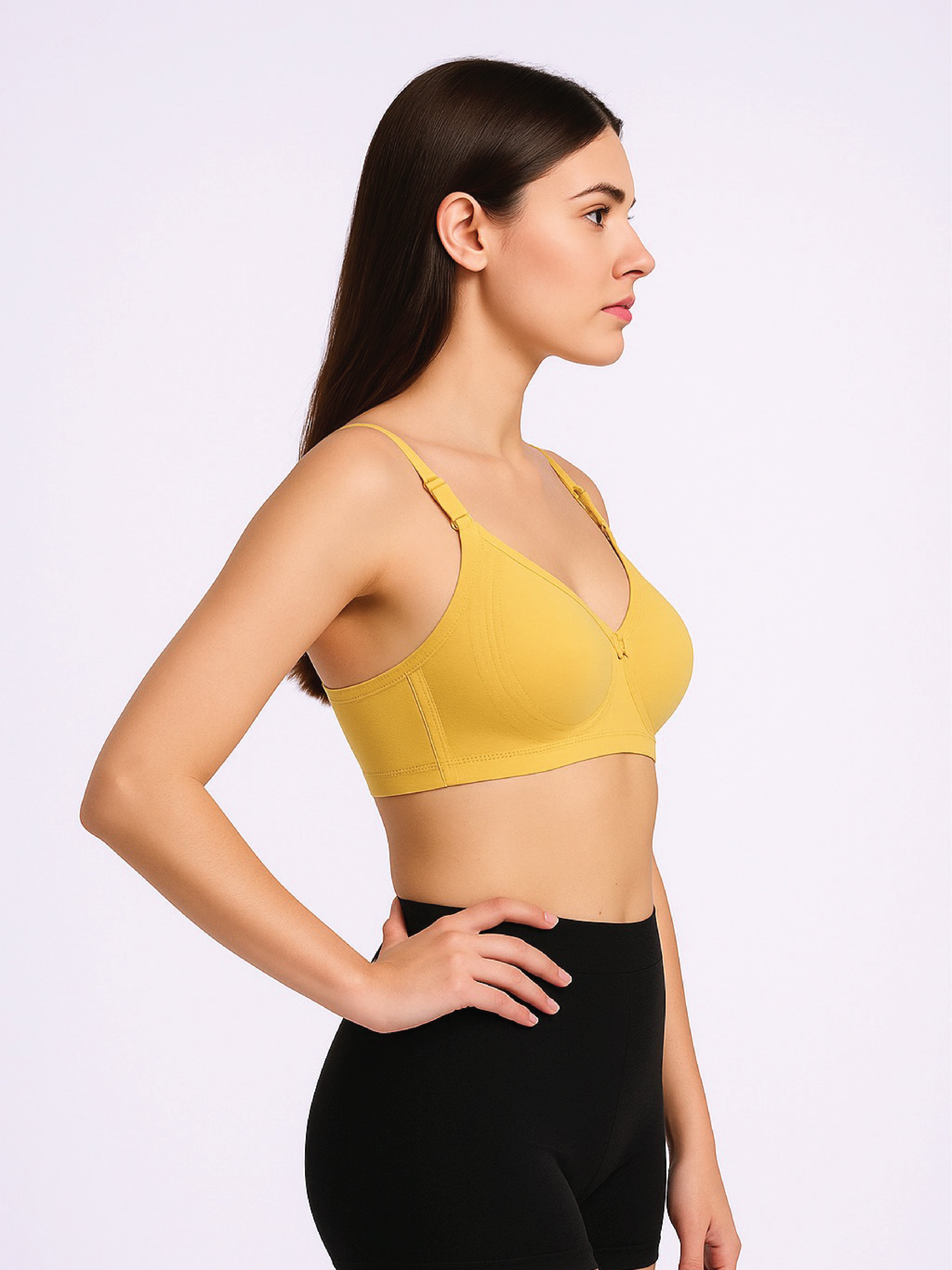 Woman wearing a yellow sports bra and black leggings on a light gray background
